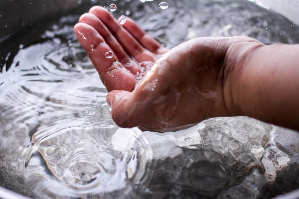 Main versant l'eau du bac de récupération d'un sèche-linge à condensation dans l'évier, geste recommandé.