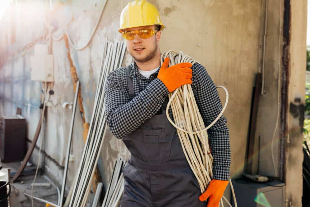 Technicien installant un câble de fibre optique en apparent le long d'un mur extérieur.