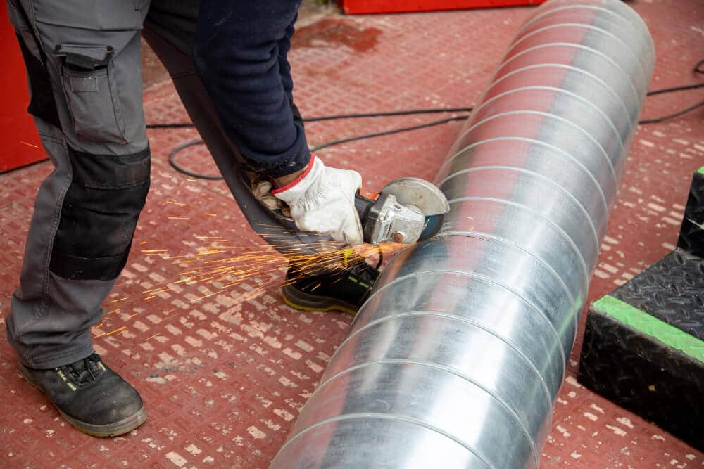 Installateur insérant un tubage flexible en inox dans un ancien conduit de cheminée en fibro-ciment.